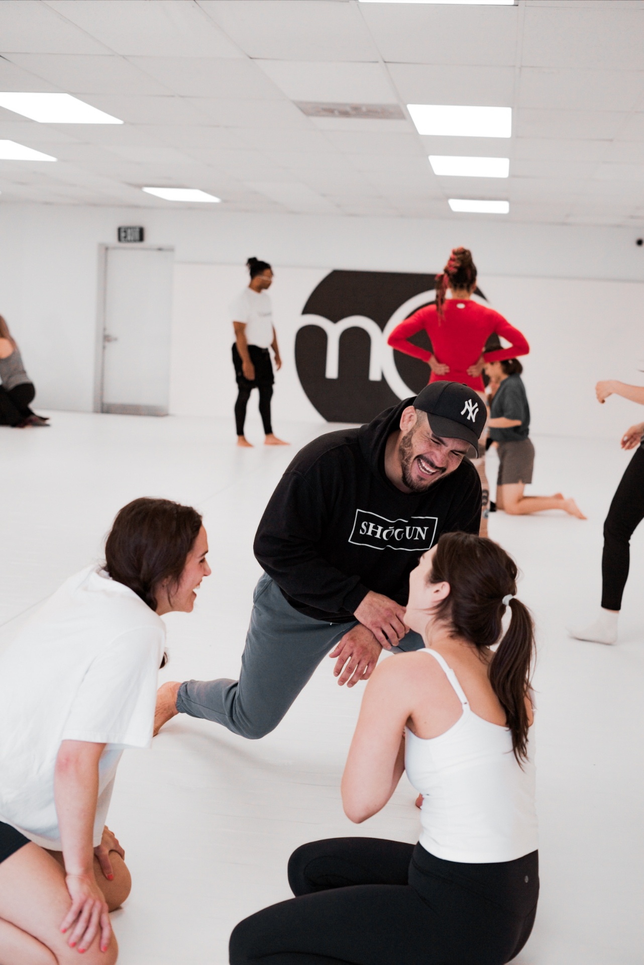 Coach Manuel laughing with students on the mat